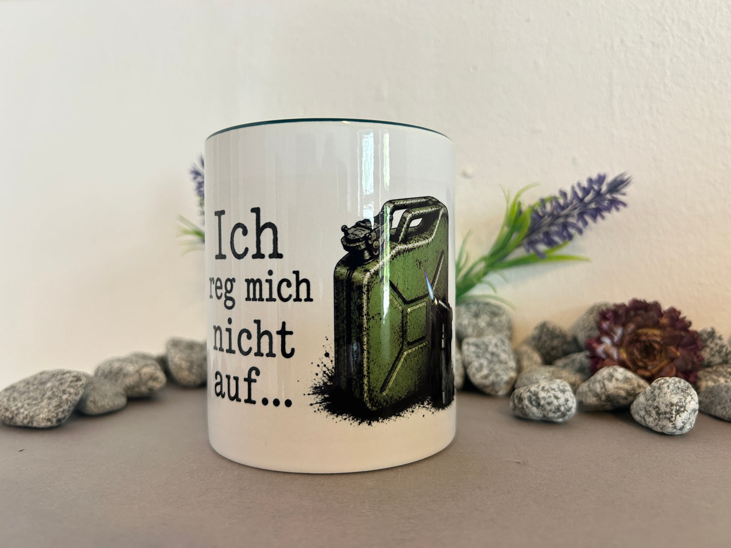 Weiße Keramiktasse mit dem Spruch „Ich reg mich nicht auf…“ und einem grünen Benzinkanister mit Gasbrenner. Das Motiv ist aus schräger Perspektive vollständig sichtbar und eignet sich als humorvolle Geschenkidee.