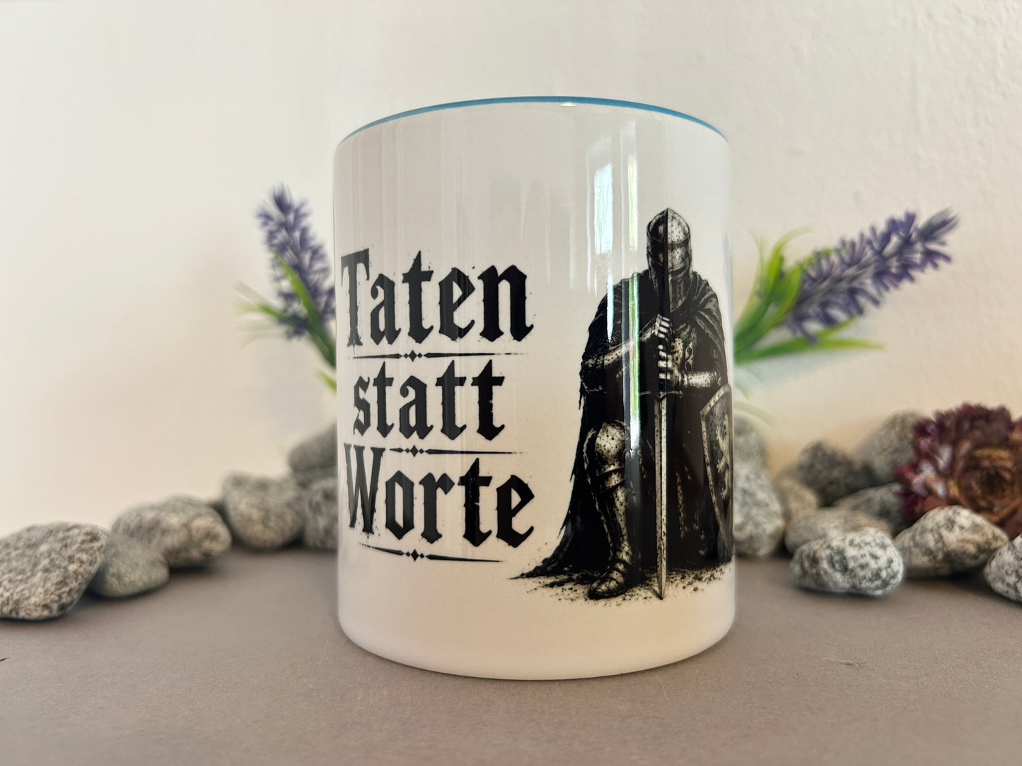 Tasse mit Spruch Taten statt Worte und Rittermotiv zwischen Natursteinen dekoriert. Geschenkidee für Männer und Mittelalterliebhaber.