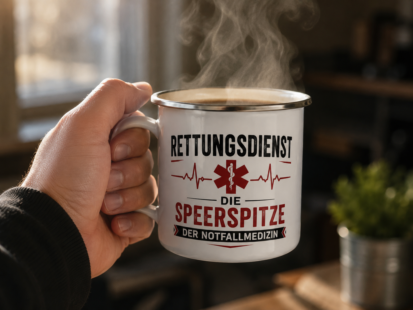 Hand hält eine dampfende Emaille-Tasse mit dem Motiv „Rettungsdienst – Die Speerspitze der Notfallmedizin“.