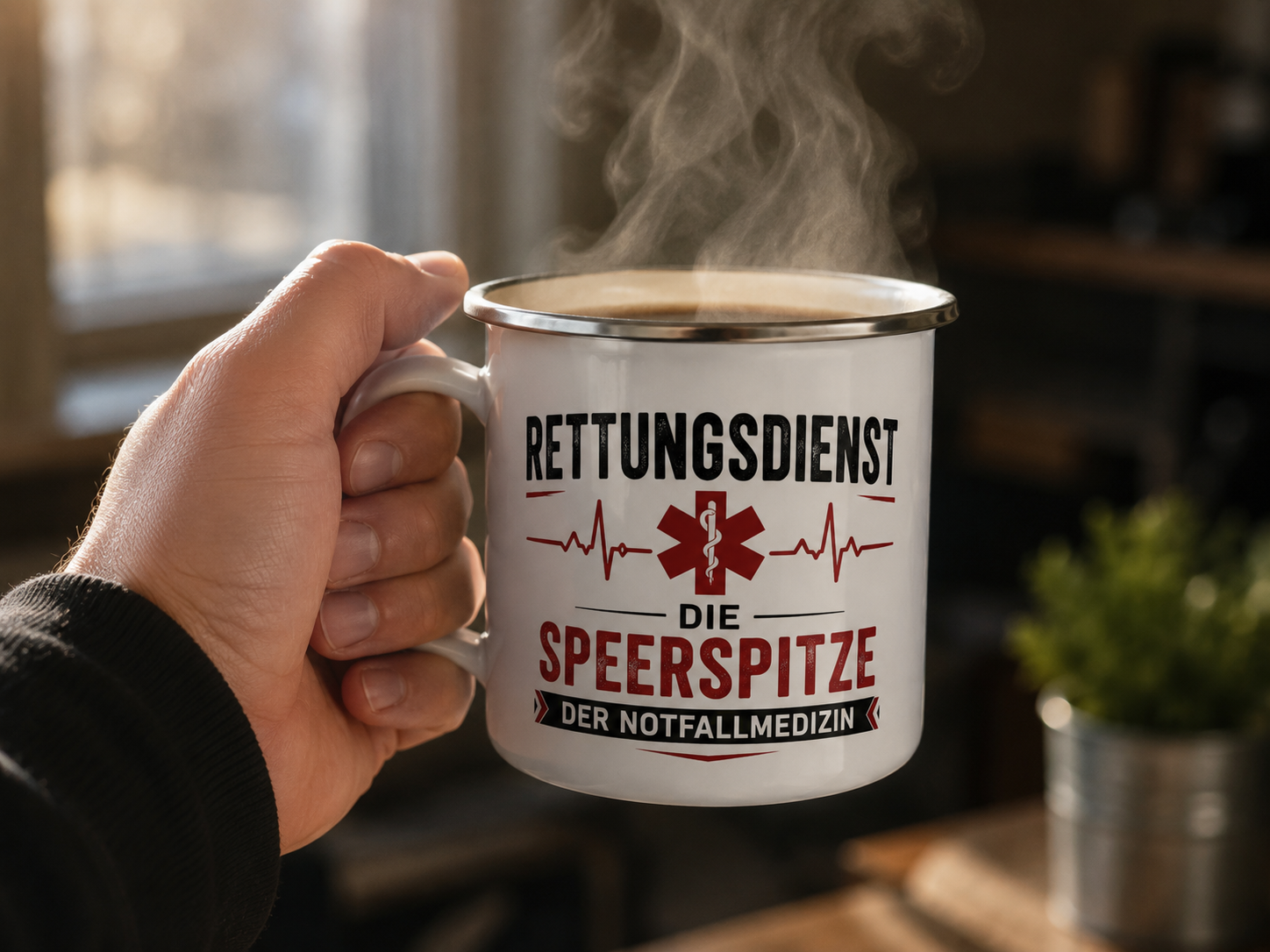 Hand hält eine dampfende Emaille-Tasse mit dem Motiv „Rettungsdienst – Die Speerspitze der Notfallmedizin“.