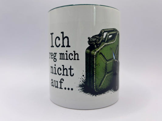 Weiße Keramiktasse mit dem Spruch „Ich reg mich nicht auf…“ sowie einem grünen Benzinkanister und Gasbrenner. Die Tasse steht dekorativ zwischen Steinen und Lavendelzweigen auf einem neutralen Hintergrund.