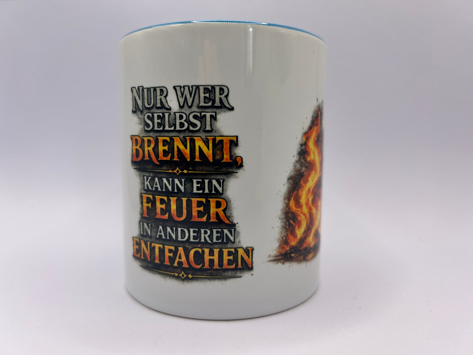 Weiße Keramiktasse mit dem Spruch „Nur wer selbst brennt, kann ein Feuer in anderen entfachen“ und dekorativem Flammenmotiv. Motivations-Tasse für Büro und Alltag.
