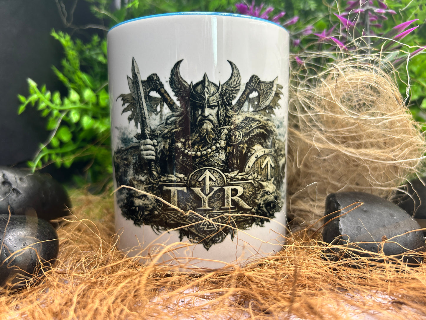 Wikinger Tasse mit Tyr Motiv dekorativ zwischen Naturmaterialien präsentiert. Geschenkidee für Fans nordischer Mythologie und Wikingerkultur.