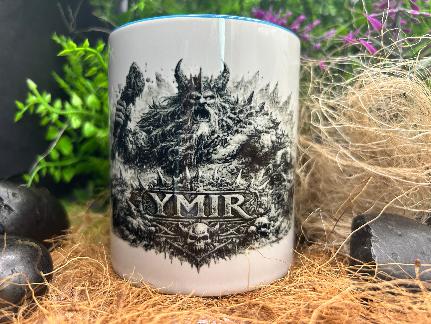 Wikinger Tasse mit Ymir Motiv dekorativ zwischen Naturmaterialien präsentiert. Ideales Geschenk für Fans nordischer Mythologie und Wikingerkultur.