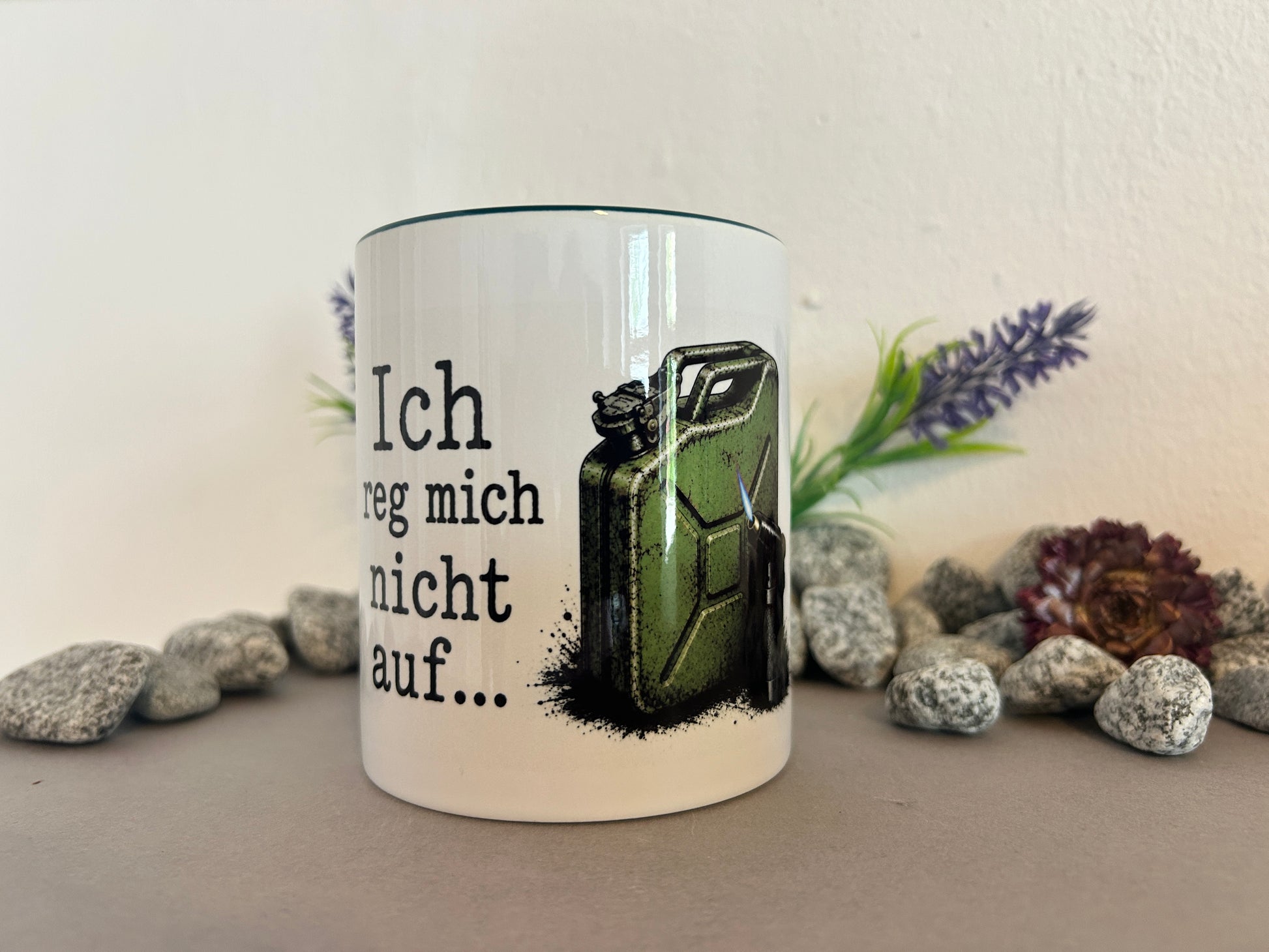 Weiße Keramiktasse mit dem Spruch „Ich reg mich nicht auf…“ und einem grünen Benzinkanister mit Gasbrenner. Das Motiv ist aus schräger Perspektive vollständig sichtbar und eignet sich als humorvolle Geschenkidee.