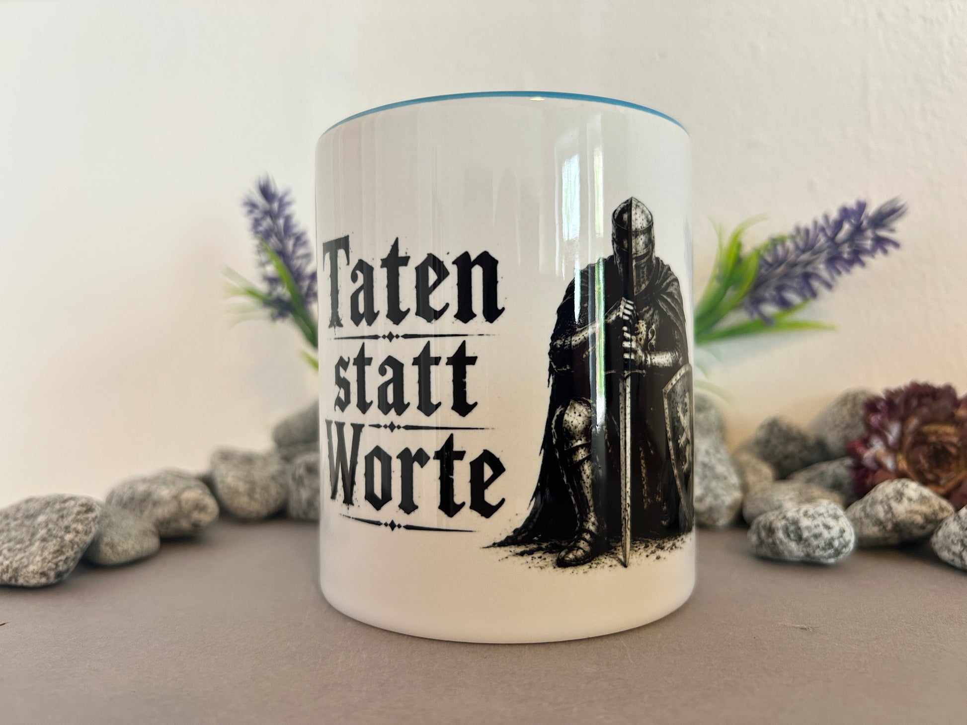 Tasse mit Spruch Taten statt Worte und Rittermotiv zwischen Natursteinen dekoriert. Geschenkidee für Männer und Mittelalterliebhaber.