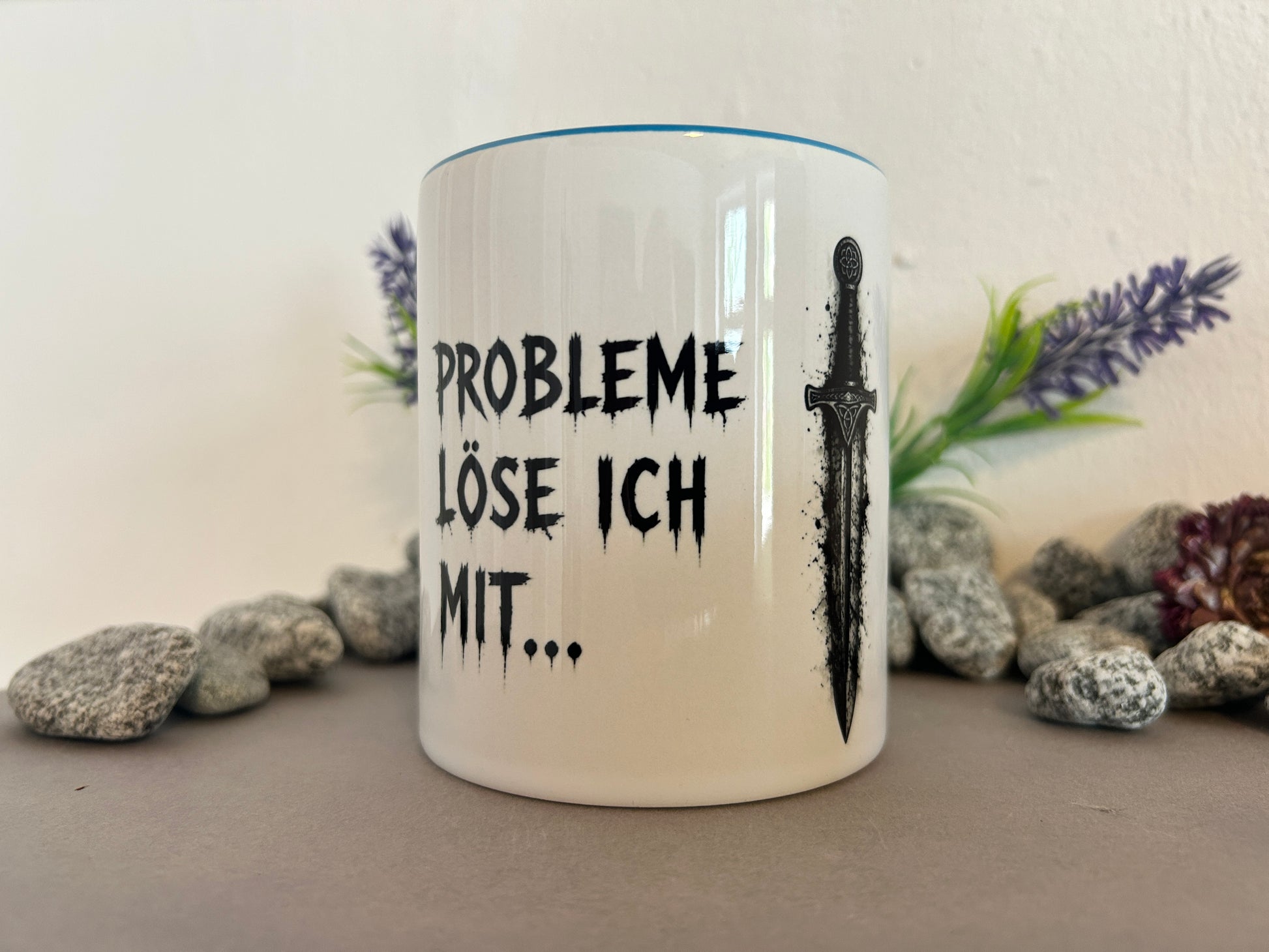 Tasse mit dem Spruch „Probleme löse ich mit…“ und Schwertmotiv dekorativ zwischen Natursteinen und Lavendel. Geschenkidee für Männer und Fantasy-Fans.