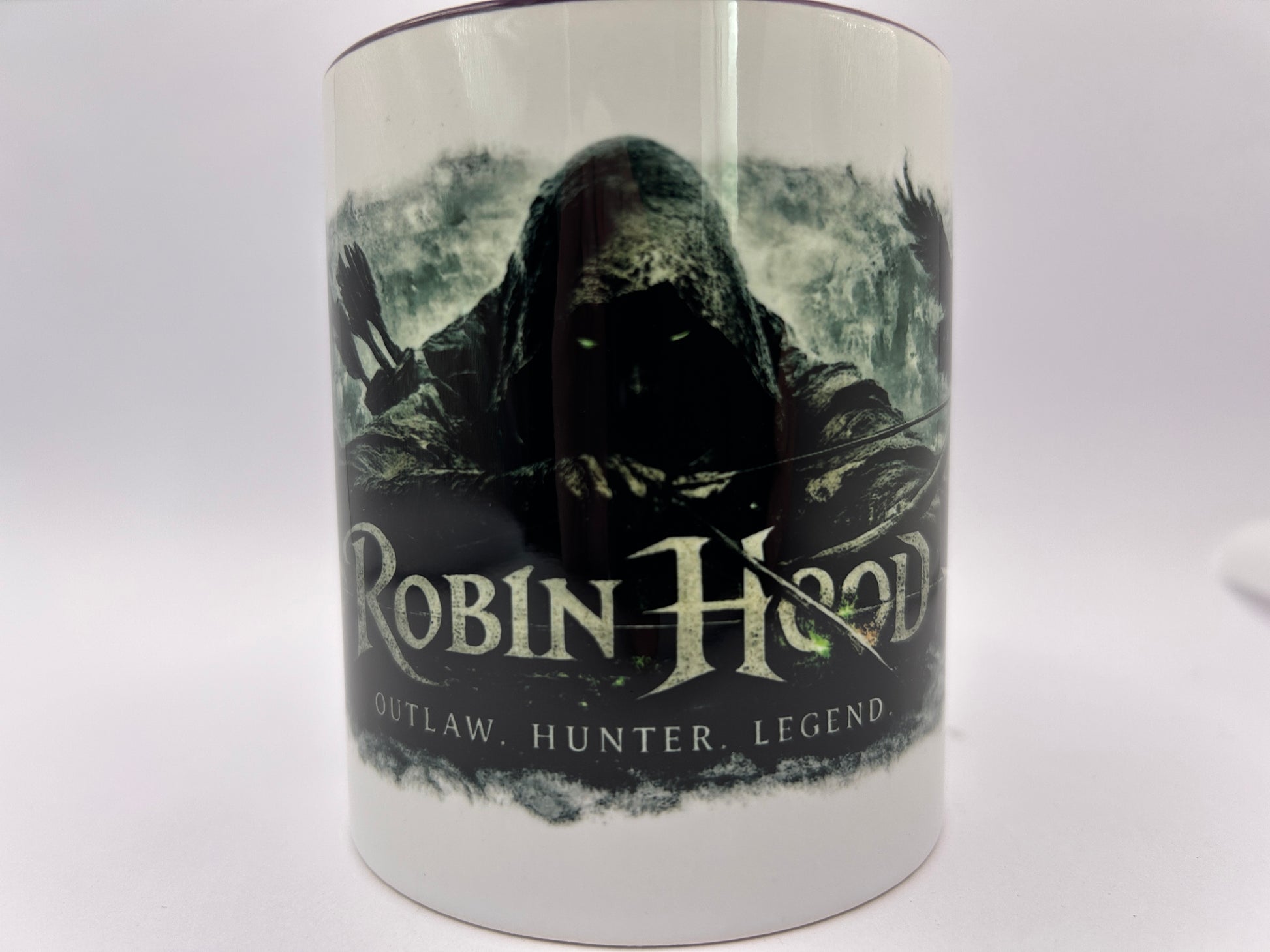Robin Hood Tasse mit düsterem Fantasy-Motiv eines geheimnisvollen Bogenschützen im Kapuzenmantel vor nebliger Waldkulisse.