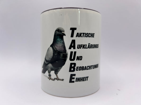 Weiße Keramiktasse mit dunklem Henkel und Rand. Das Motiv zeigt eine Taube mit taktischer Weste neben dem Schriftzug „TAUBE – Taktische Aufklärungs- und Beobachtungseinheit“ auf weißem Hintergrund.