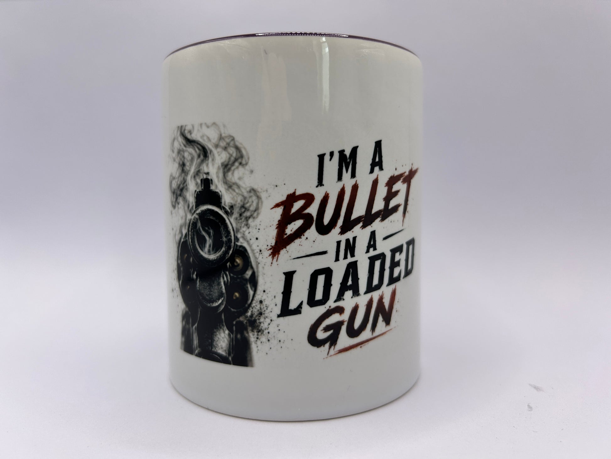 Keramiktasse mit Revolver Motiv und Spruch I'm A Bullet In A Loaded Gun auf weißem Hintergrund
