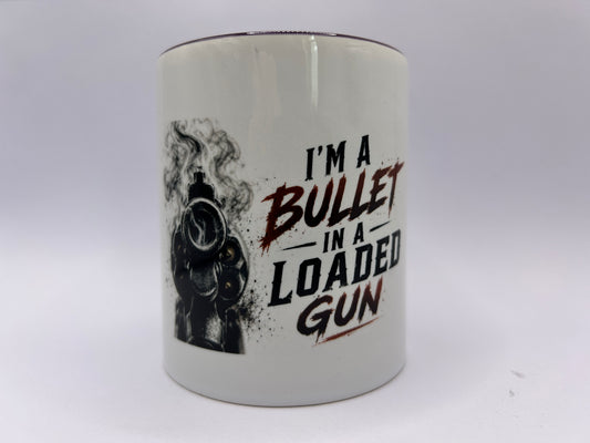 Keramiktasse mit Revolver Motiv und Spruch I'm A Bullet In A Loaded Gun auf weißem Hintergrund
